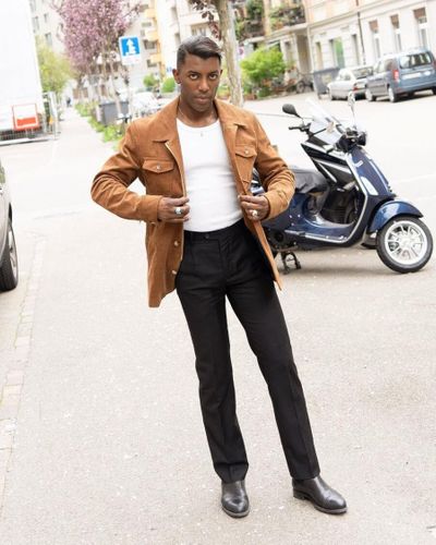 Man in leather pants and dress shirt on a scooter. Created with